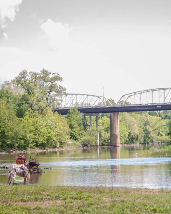 April owner of piney paws and dog during a walk looking at the bridge in bastrop